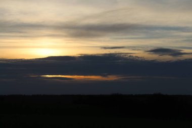 Almanya 'da güneşli bir tarlanın üzerinde gün batımının güzel bir görüntüsü.