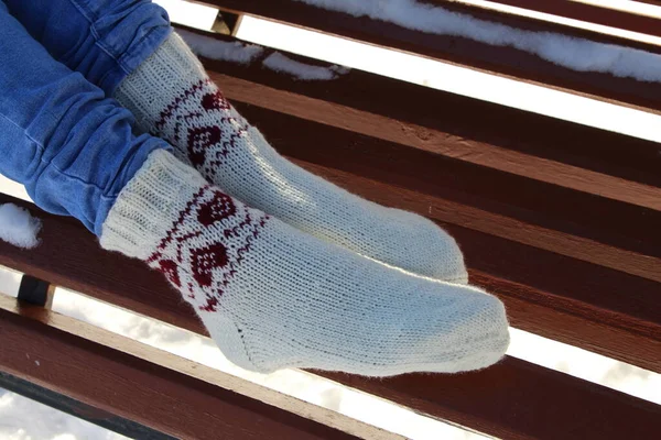 female feet wearing knitted socks on wooden stairs in winter park