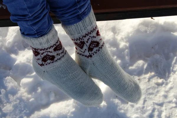 woman \'s feet wearing socks and mittens on snow