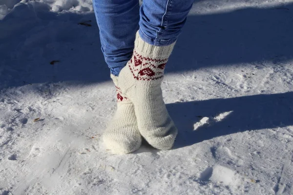 woman legs in winter boots and socks in snow