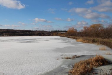 Arka planda birkaç ağaç olan donmuş bir göl.