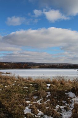 Bir gölü ve birkaç bulutu olan bir arazi.