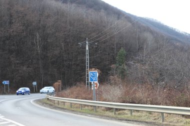 Ağaçlar ve yeşilliklerle çevrili güzel bir yol manzarası.