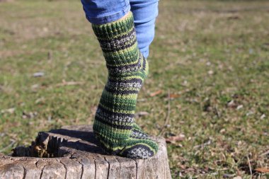 Kütüğe örülmüş çorap giyen bir kadının dikey görüntüsü.