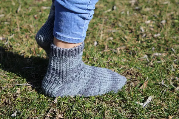 a woman in the blue socks is walking on a green grass in the park.