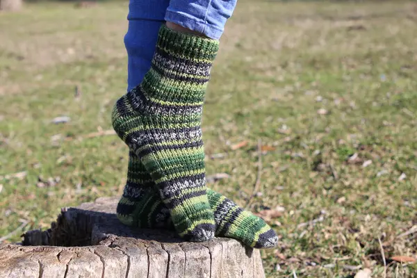 woman in green striped socks and knitted woolen socks in the forest