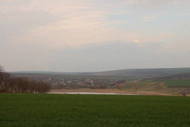 Bir köy ve bulutlu bir gökyüzü olan kırsal alan. Akşamları kırsaldaki köy..