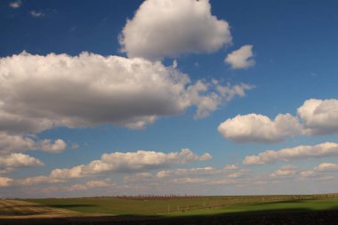 Yazın beyaz bulutları ve mavi gökyüzü olan güzel bir arazi.