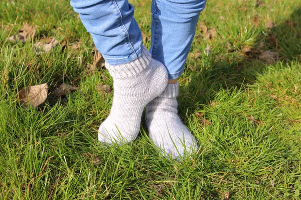 woman wearing warm knitted socks on grass, closeup