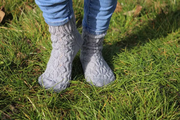 woman wearing warm knitted socks on a green grass
