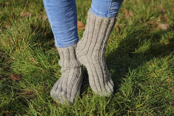 woman \'s legs in knitted socks on green grass
