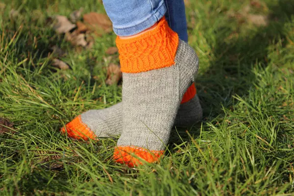 woman \'s feet in a green knitted sweater and socks on the grass