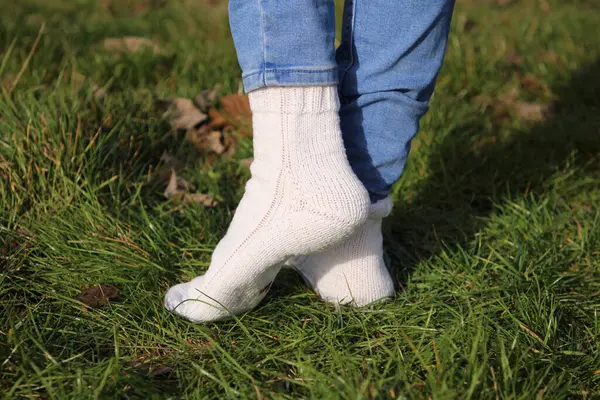 a woman \'s feet in a green knitted sweater and a socks in a forest on a warm autumn day