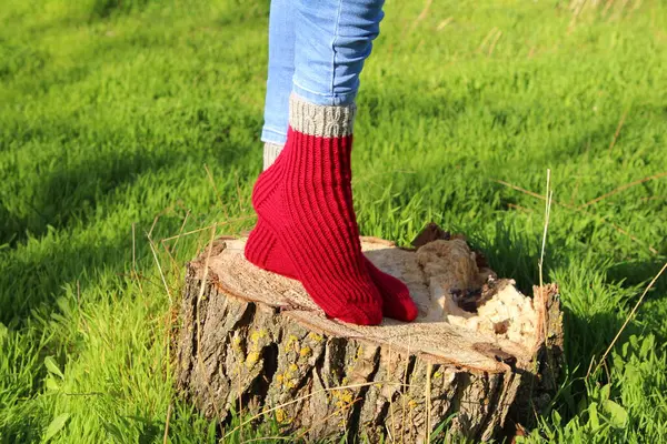 woman legs with red wool socks on green grass background, closeup