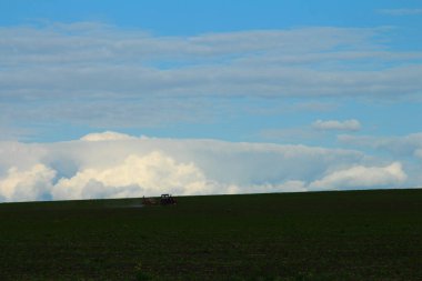 Mavi gökyüzü ve büyük beyaz bulutları olan güzel bir arazi.