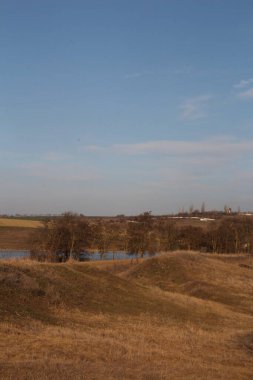 bahar tarlası ve mavi gökyüzü. Köyün arka planında bulutlar var.