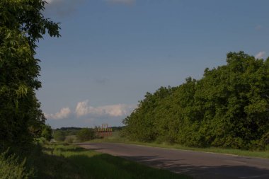 Arka planda bulutlu gökyüzü ve yeşil bir tarlası olan eski bir evin dikey görüntüsü.