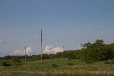 Arka plandaki açık mavi gökyüzünün altında bir güç iletim hattının dikey görüntüsü.