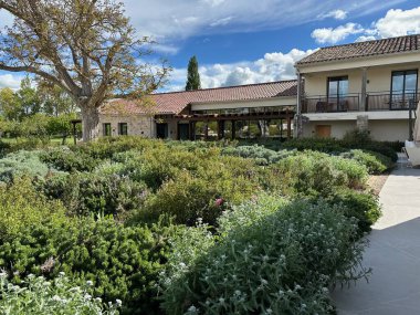 Büyük beyaz bir ev ve mavi gökyüzü olan güzel bir bahçenin dikey görüntüsü.