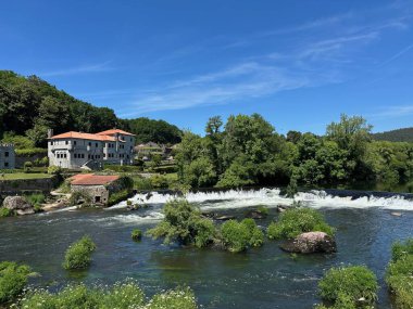 Yeşil ve mavi gökyüzüyle çevrili bir nehrin dikey görüntüsü.