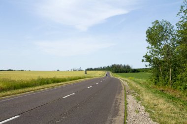 İlkbaharda kırsal kesimde asfalt yol. Letonya.