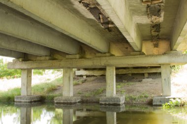 Ormanda bir sürü taş olan paslı bir köprü.