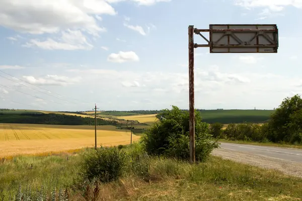 Çiftlik arazisindeki eski paslı metal tabela. Uzağa giden yol..