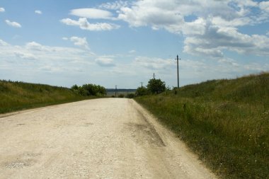 Çimenli ve mavi gökyüzü olan bir arazide toprak yol