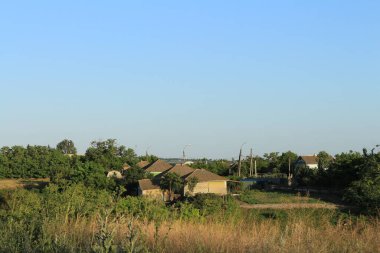 Kırsal alanda evler, ağaçlar ve mavi gökyüzü
