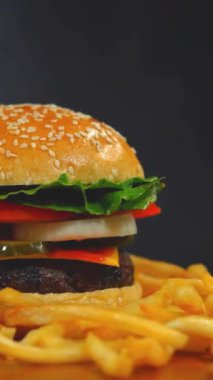 Hamburger ve patates kızartması ahşap masada dönüyor. Sağlıksız Diyet Dengeli Yeme Alışkanlıkları Lezzetli Yemekler. Sağlıksız yemek, fast food, lezzetli sığır burger, peynir, restoran, kahvaltı. Hamburger.