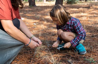 Anne ve oğul ormanda bir çadırdan kazma hazırlıyorlar.