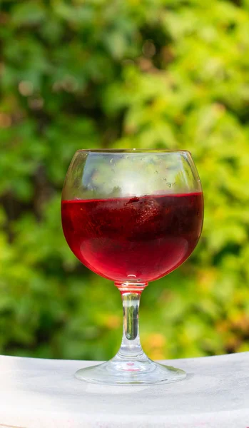 Glass with a red cocktail with a green background of nature