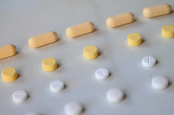 Orange, yellow, and white medicine pills up close