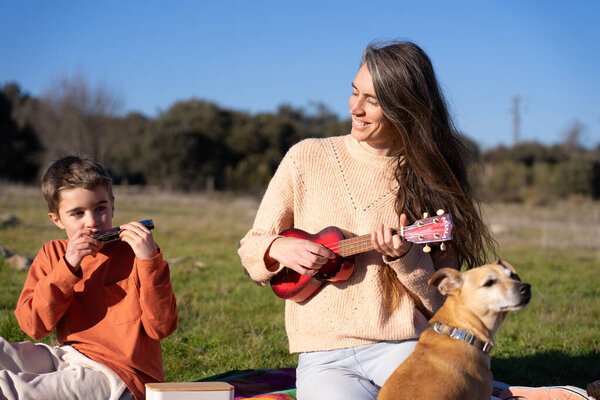 Mother and son playing music with their dog outdoors