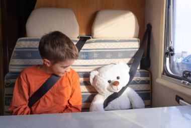 Çocuk emniyet kemerleriyle oyuncak ayısıyla seyahat ediyor.