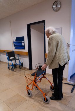 Rehabilitasyon hastanesinde yürüyen yaşlı bir kadın.