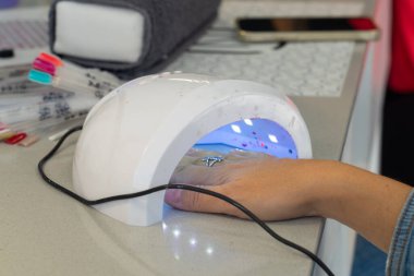 Manikür merkezinde tırnaklarını kurutan bir kadın.