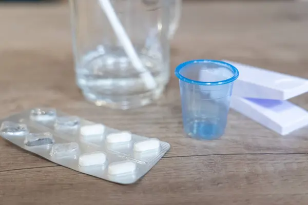 Pills with a glass of water, a pill cutter and a small glass