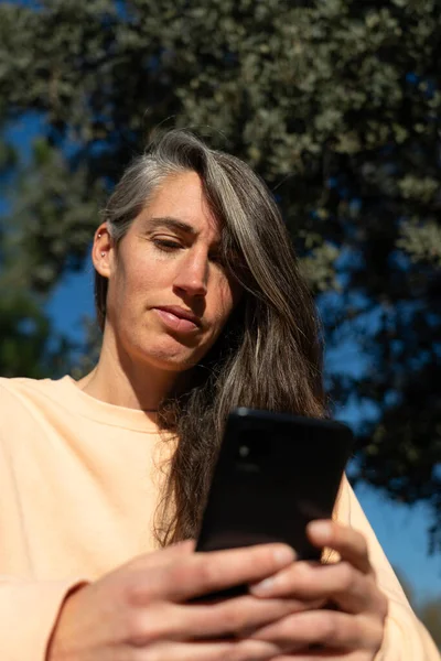Woman looking at mobile screen seen from below in nature
