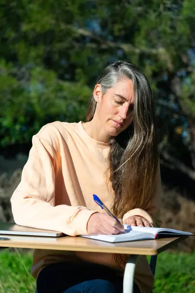 Entrepreneur woman working outdoors writing things down in a planner at a desk