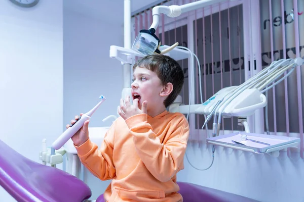 Boy in a dentist\'s chair with an electric toothbrush