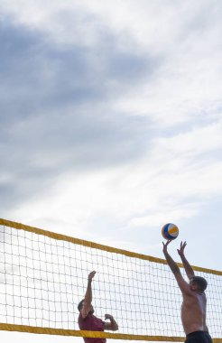 Sahilde voleybol oynayan iki adam.