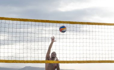 Mutlu adam plaj voleybolu oynuyor.