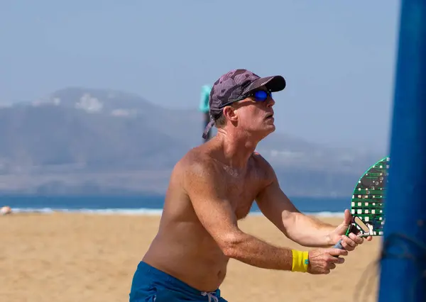 Healthy man over 50 years old playing beach tennis in summer