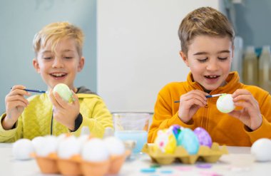 Çocuklar Paskalya için yumurta boyarken eğleniyor.
