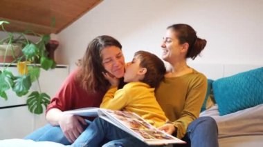 İki anne ve bir çocuktan oluşan LGBT ailesi oyun oynuyor, sarılıyor ve gülüyor.