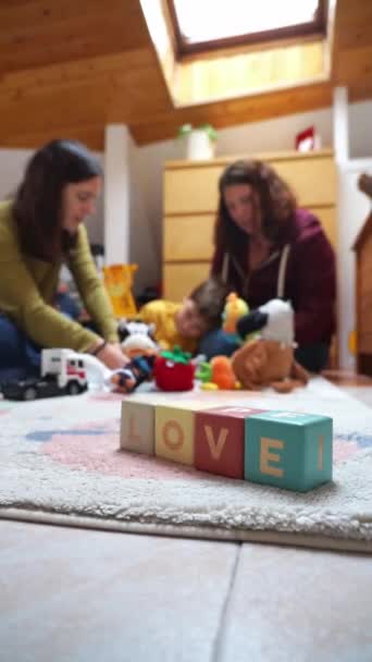 Lgbtqia 2人の母親とその息子の家族は 子供の部屋で一緒に遊んで いくつかの玩具ブロックと という言葉 — ストック動画