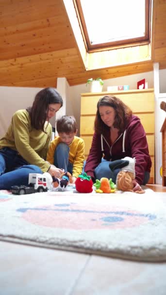 部屋のカーペットで一緒に遊んでいる2人の母親と息子の家族 — ストック動画