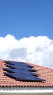 Bulutlu mavi gökyüzü olan bir evin çatısındaki güneş panelleri