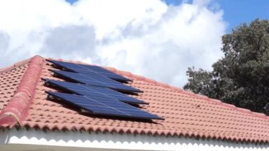 Bulutlu mavi gökyüzü olan bir evin çatısındaki güneş panelleri